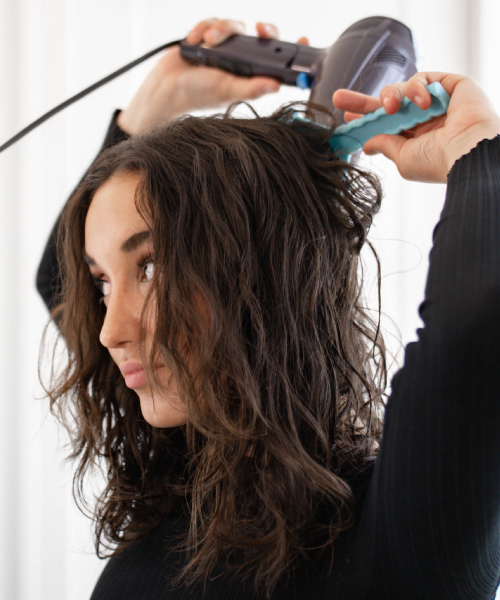 woman using the CLM Volumizer to do her hair